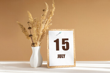 july 15. 15th day of month, calendar date.White vase with dried flowers on desktop in rays of sunlight on white-beige background. Concept of day of year, time planner, summer month