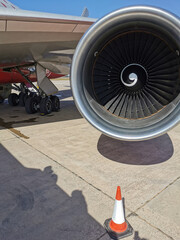 An aircraft engine on the wing of an airplane parked at Paphos Airport against a beautiful blue sky.