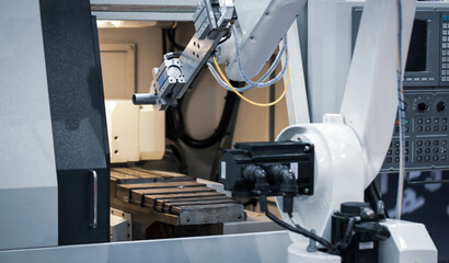 Modern factory. Robot feed workpiece on CNC lathe machine. Industrial manufacturing.