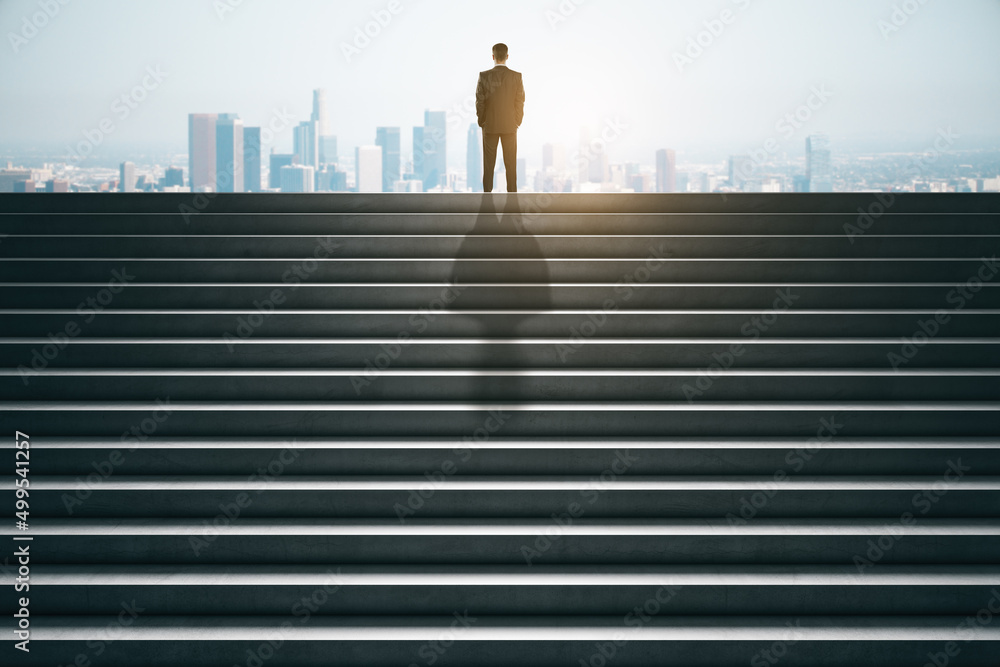Poster back view of businessman on top of concrete stairs looking into the distance on daylight city backgr