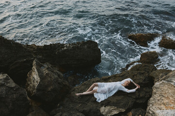beautiful woman lying on rocky coast with cracks on rocky surface unaltered