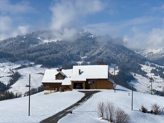 Indigenous alpine huts and wooden cattle stables on Swiss pastures covered with fresh white snow cover, Nesslau - Obertoggenburg, Switzerland (Schweiz)