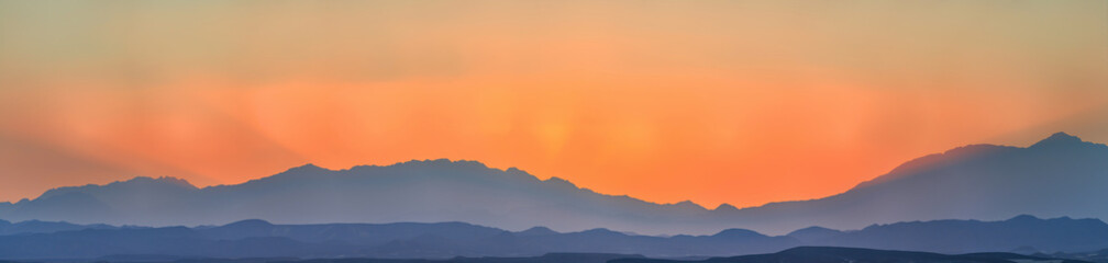 Silhouettes of mountains and a beautiful orange sky at sunset.