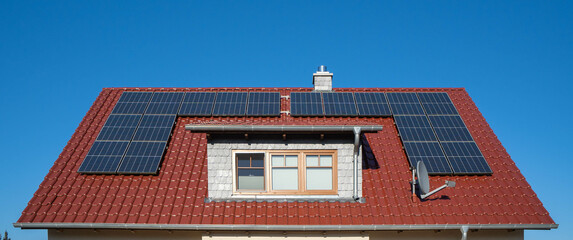 red tiled roof of a house with solar panels of a photovoltaic system
