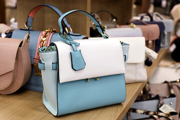 Female handbags on rack in a store. Different colors of spring and summer female purses - obrazy, fototapety, plakaty