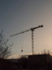 Silhouette of a tall crane and construction site for commercial office of residential property. Construction industry. Modern technology. Investment.