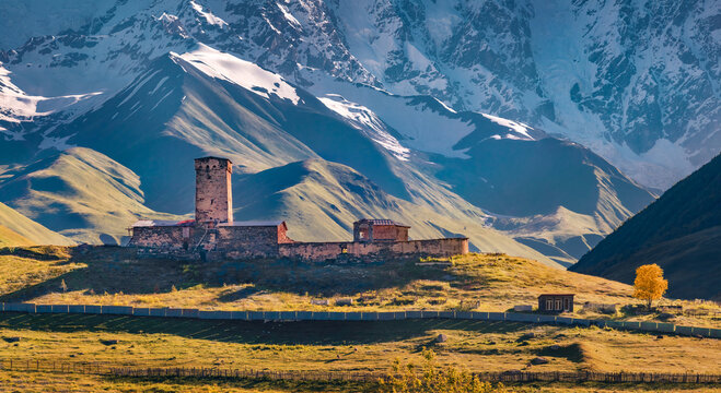Gorgeous autumn view of ancient Lamaria church in Ushguli village. Splendid morning view of snowy Shkhara hills in Upper Svaneti, Caucasus mountains, Georgia, Europe. Traveling concept background.