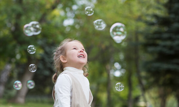 happy and healthy childhood. Child girl playing with soap bubbles in summer park.