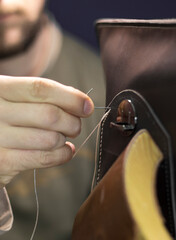 Obraz na płótnie Canvas craftsman sews leather details with thread