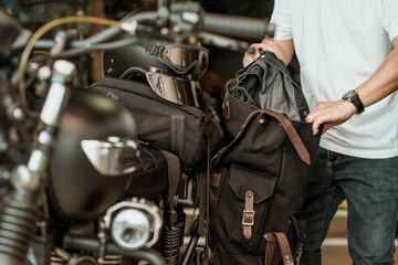 Fototapeta na wymiar rider take the clothes out of the side bag or saddlebags of motorcycle after trip ,motorcycle travel concept. selective focus