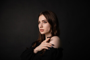 Fototapeta premium Portrait of a beautiful woman with long hair on a dark background.Girl with a charming smile.