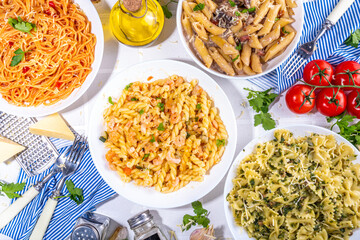Set of pasta with different sauces on white tiled background. Spaghetti, farfalle, penne, fusilli pasta with seafood, spinach, carbonara, tomato sauce. Italian dinner, Mediterranean food concept