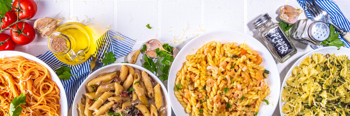 Set of pasta with different sauces on white tiled background. Spaghetti, farfalle, penne, fusilli pasta with seafood, spinach, carbonara, tomato sauce. Italian dinner, Mediterranean food concept