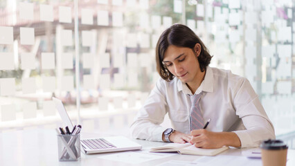 Business concept, Businessman analyzing data and writing idea in notebook while working in office