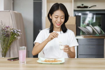 Home relaxation concept, Young woman eating yogurt and crackers for snack while relaxation at home