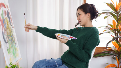 Creative of art concept, Young asian woman hold paintbrush in front of canvas to measure proportion