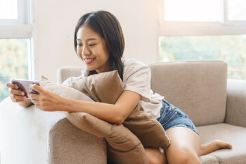 Cozy lifestyle concept, Young woman sitting on couch and use smartphone to watching movie at home