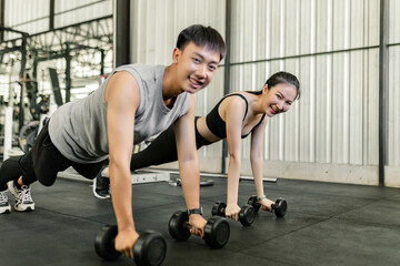 exercise concept The female and male members of the gym doing the basic renegade row posture with dumbbells while looing at each other’s face