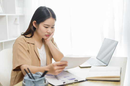 Online lifestyle concept A female home worker seriously concentrating on reading some data from the paper .