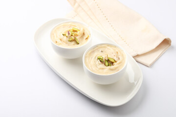 Shrikhand is an Indian sweet dish made of strained curd,garnished with dry fruits and saffron. Served in a ceramic bowl.Selective focus