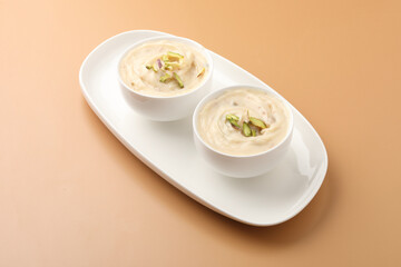 Shrikhand is an Indian sweet dish made of strained curd,garnished with dry fruits and saffron. Served in a ceramic bowl.Selective focus