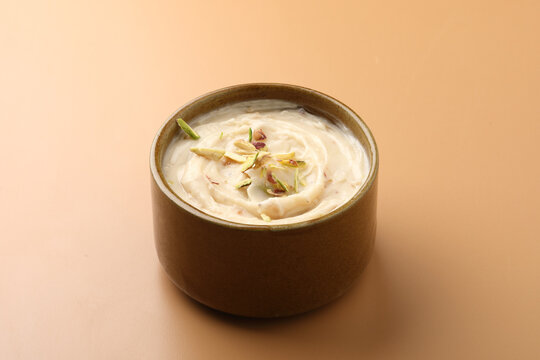 Shrikhand is an Indian sweet dish made of strained curd,garnished with dry fruits and saffron. Served in a ceramic bowl.Selective focus