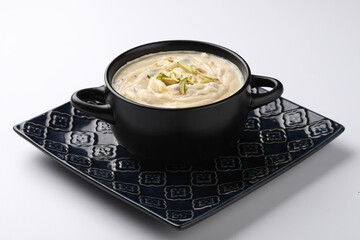 Shrikhand is an Indian sweet dish made of strained curd,garnished with dry fruits and saffron. Served in a ceramic bowl.Selective focus