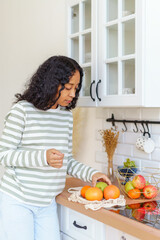 African-American taking out apples and oranges after going at grocery store with eco-bag