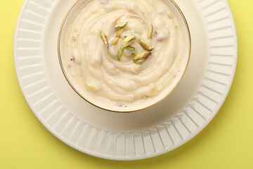 Shrikhand is an Indian sweet dish made of strained curd,garnished with dry fruits and saffron. Served in a ceramic bowl.Selective focus