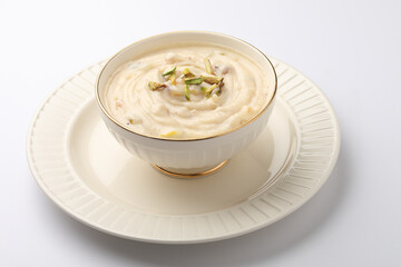 Shrikhand is an Indian sweet dish made of strained curd,garnished with dry fruits and saffron. Served in a ceramic bowl.Selective focus