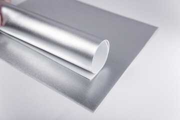 Rolled silver sheet of cardboard. Sheets of shiny isolon. Metallic paper.