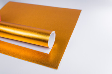 A rolled up gold sheet of cardboard. Sheets of shiny isolon. Gold paper.