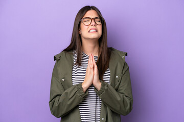 Young Brazilian woman isolated on purple background keeps palm together. Person asks for something