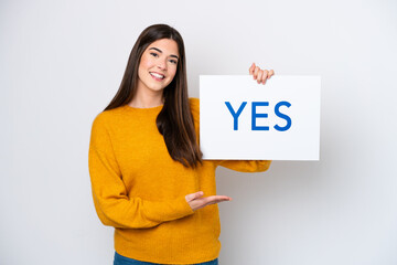 Young Brazilian woman isolated on white background holding a placard with text YES with happy expression