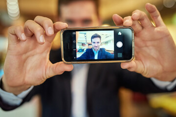 This is one for the business profile. Shot of a young businessman taking a selfie while sitting in a coffee shop.