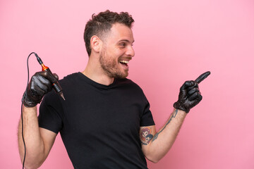 Tattoo artist brazilian man isolated on pink background pointing finger to the side and presenting...