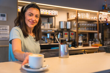 Smiling waitress in the cafeteria with the coffee prepared handing it to the client, the restrictions due to covid are removed and the mandatory use of masks is removed