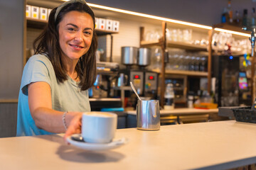 Smiling waitress in the cafeteria with the coffee prepared handing it to the client, the restrictions due to covid are removed and the mandatory use of masks is removed