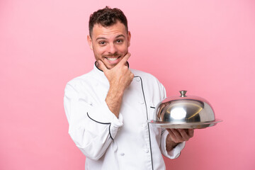 Young Brazilian chef with tray isolated on pink background happy and smiling