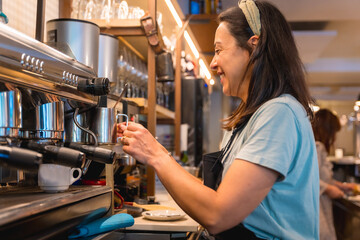 Smiling waitress in the cafeteria preparing the coffee in the coffee machine, the restrictions due to covid are removed and the mandatory use of masks is removed