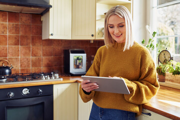 Mature woman using digital tablet at home in a kitchen