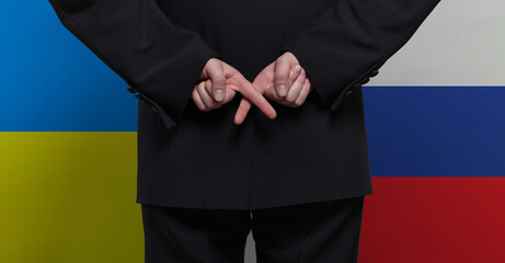 Man with crossed fingers on Ukrainian and Russian flags background