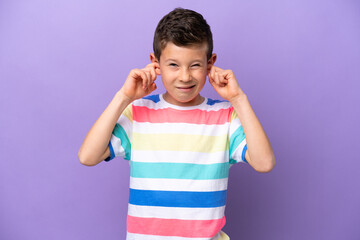 Little boy isolated on purple background frustrated and covering ears