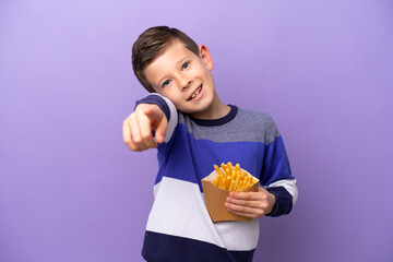 Little boy holding fried chips isolated on purple background pointing front with happy expression