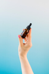 A mock-up of a brown dropper with skin oil in a woman's hand.
