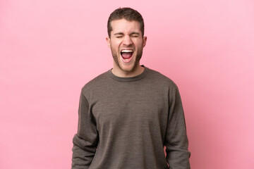 Young caucasian man isolated on pink background shouting to the front with mouth wide open