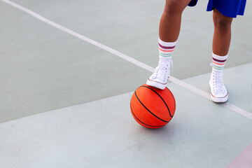 foot holding a basketball on the court