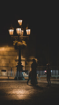 Two Kids With His Mother Playing Under The Streetlight