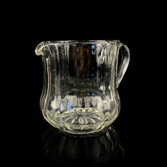 crystal antique jug for drinks. vintage glass vessel for water on a black isolated background