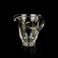 crystal antique mug with floral pattern. vintage glass gravy boat on black isolated background